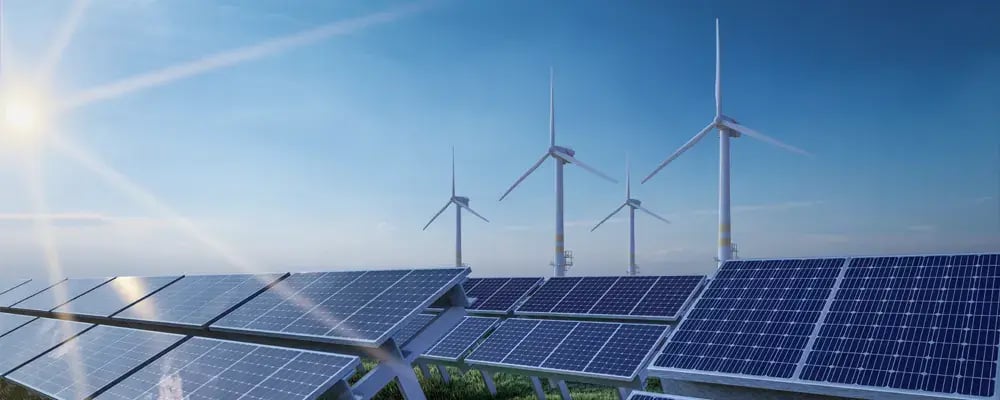 Painéis solares sobre um campo com usinas eólicas ao fundo.